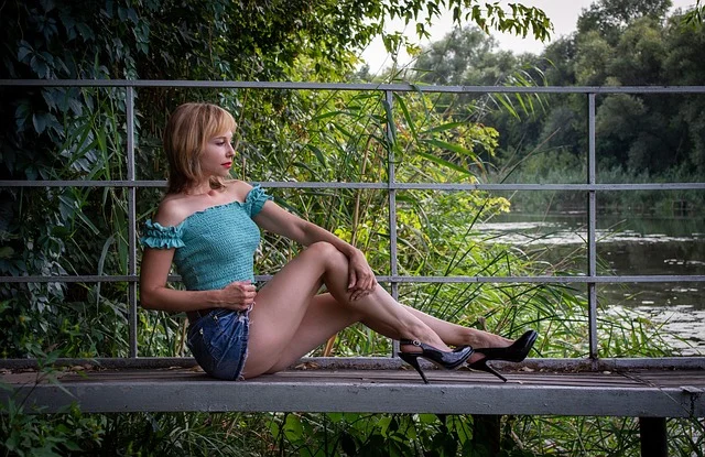 A woman wearing a short denim skirt and heels posing outdoors