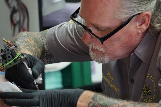 A tattoo artist sketching a detailed lotus flower design in a sketchbook.