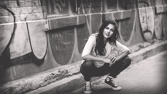 A woman crouching in Converse high-top sneakers outdoors