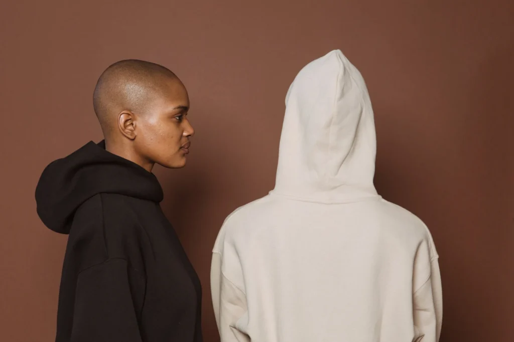 Best essentials hoodie dupes: Two people wearing oversized hoodies in black and beige