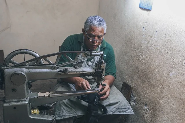 A cobbler using a shoe repair sewing machine in a workshop