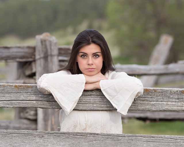 Woman looking thoughtfully at her wardrobe with assorted summer clothing items.