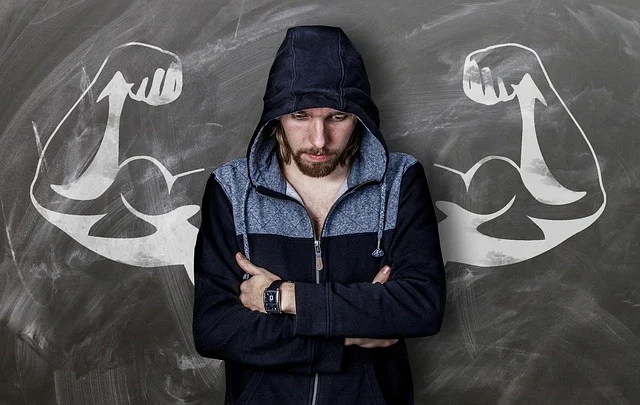 A man wearing a zip-up hoodie standing in front of chalk muscles