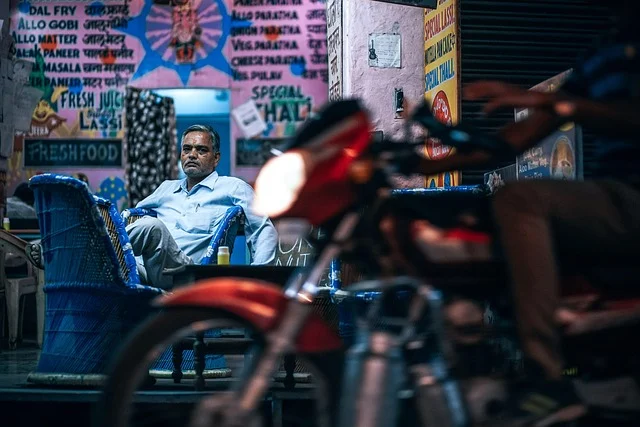 A man sitting outside a small street restaurant or shop