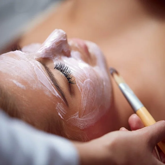 A woman receiving a cosmetic facial treatment applied with a brush