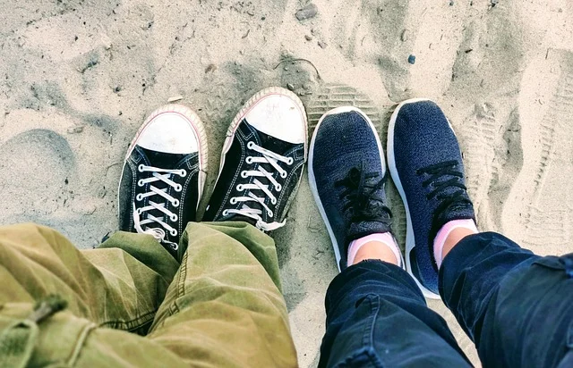 Top-down view of two people wearing casual sneakers on sand