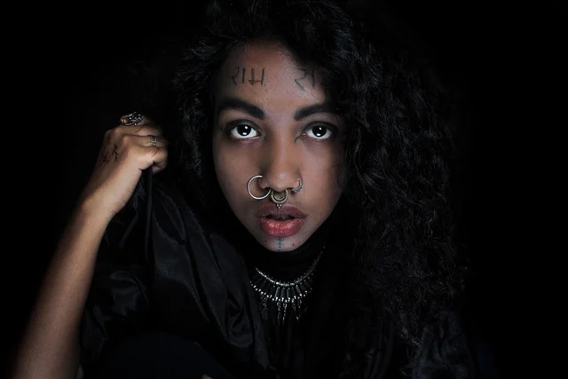 Portrait of a woman with curly hair and nose piercings