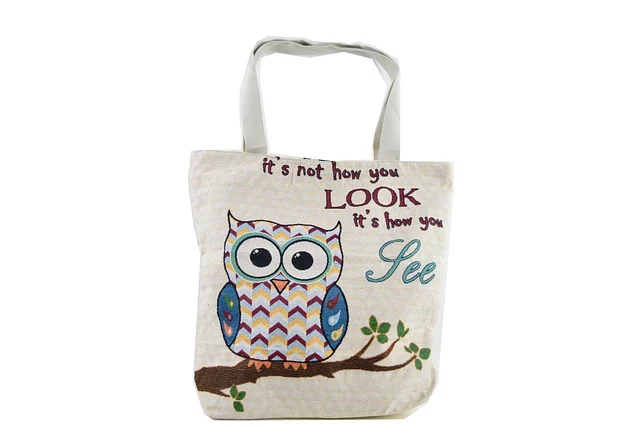 A canvas tote bag with an owl design and text