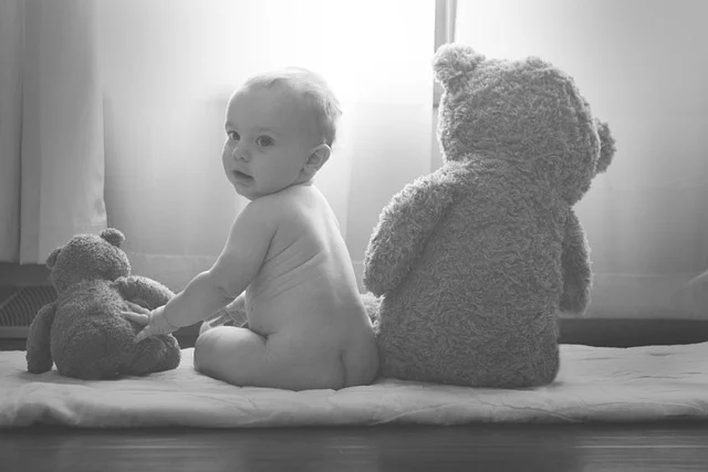 A baby sitting on a mat next to teddy bears