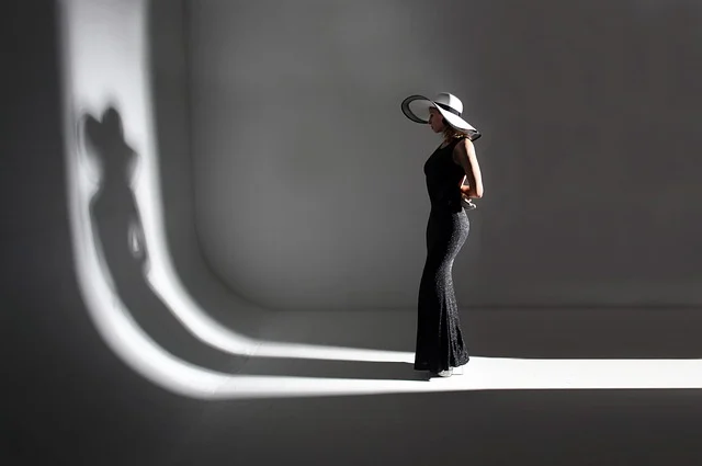 A woman in a black dress and wide-brimmed hat in studio