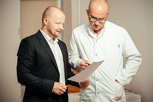 A doctor and a man reviewing documents together in a clinic