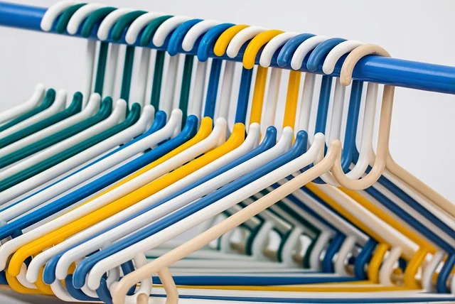 A row of colorful plastic clothes hangers on a rack