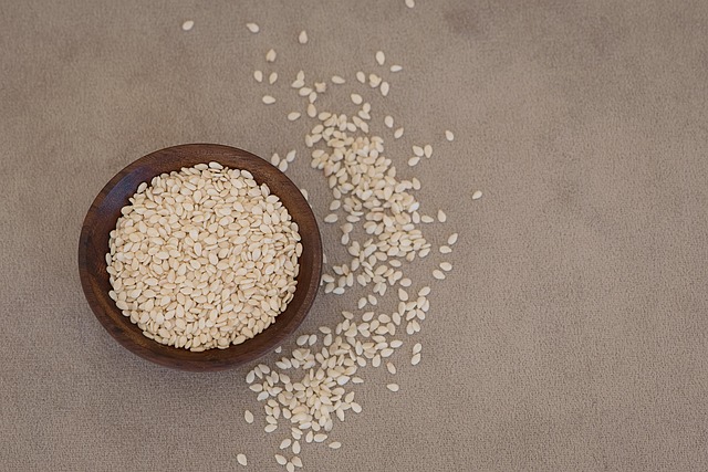 Close-up of light-colored sesame seeds and a bottle of pale, clear sesame oil (sesame oil and toasted sesame oil)