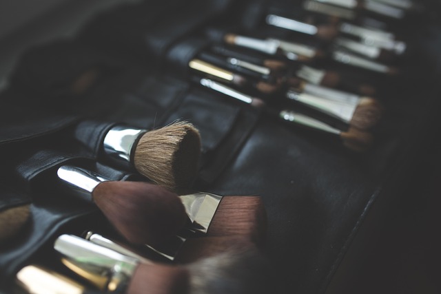 close-up of a makeup artist's hand holding a blush pink blush compact with a fluffy brush