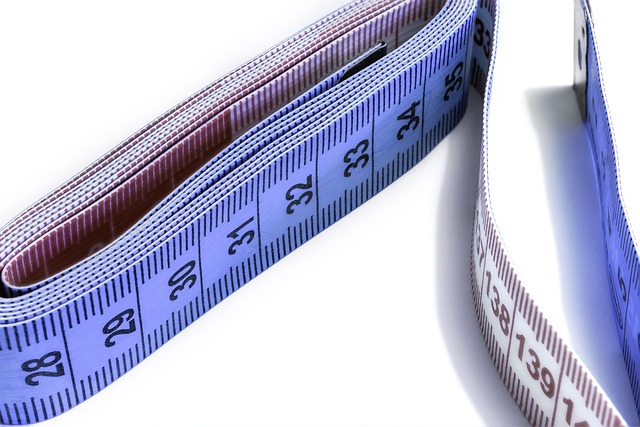 A close-up of a measuring tape on black leather pants, highlighting key areas for fit like the waist and thigh.