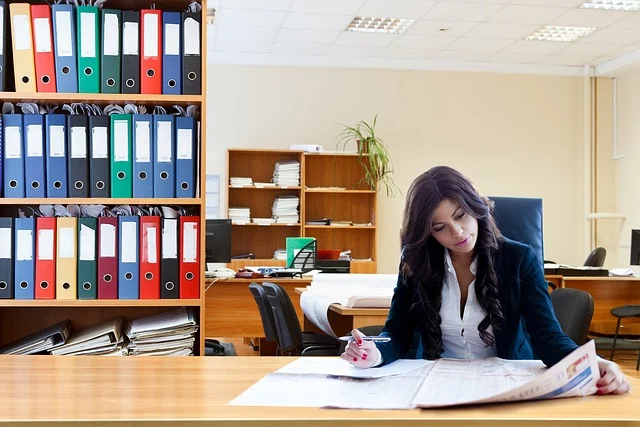 A woman sitting at a desk reviewing documents in an office