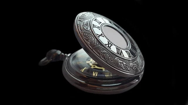 An ornate vintage silver pocket watch on a black background