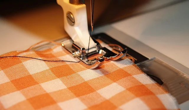 A sewing machine needle stitching orange patterned fabric