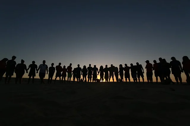Silhouetted group of people holding hands at sunset