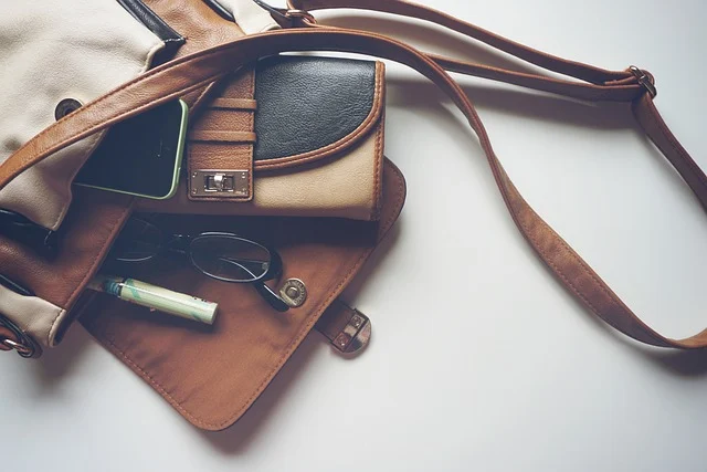 An open leather handbag with a wallet, phone, and glasses