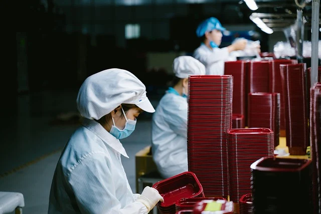 Factory workers wearing masks and hairnets assembling packaging containers