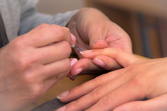 Fingers with a nail file creating the almond shape on a short nail