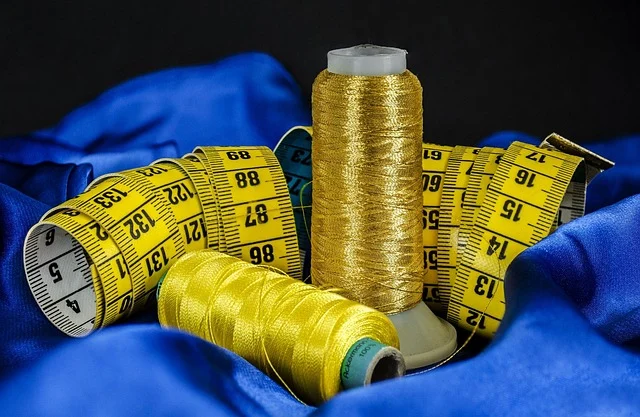 Spools of thread and measuring tape on blue fabric