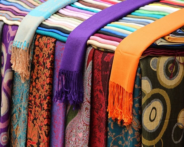 A colorful display of folded and draped scarves
