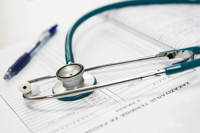 A stethoscope resting on medical appointment forms and a pen