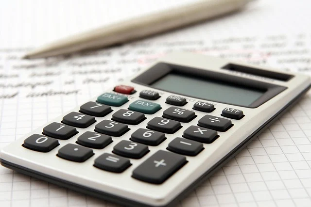 A calculator resting on a piece of paper with a pen