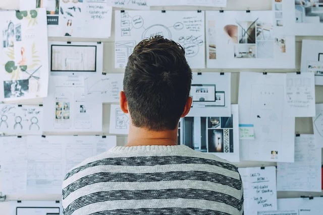 A person looking at a wall covered with sketches and plans