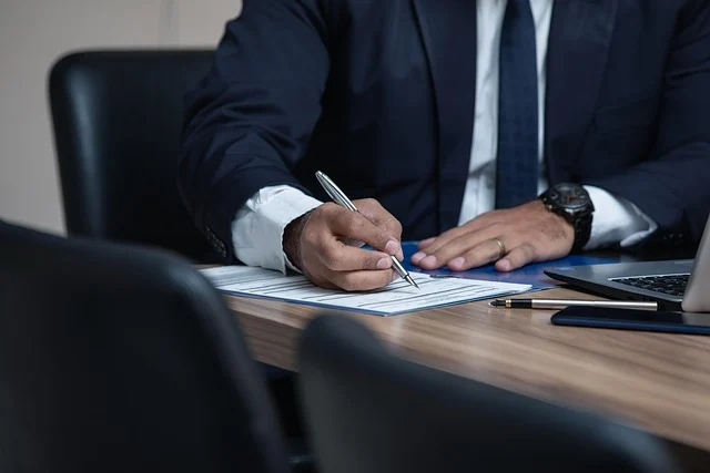 A professional in a suit filling out documents at a desk