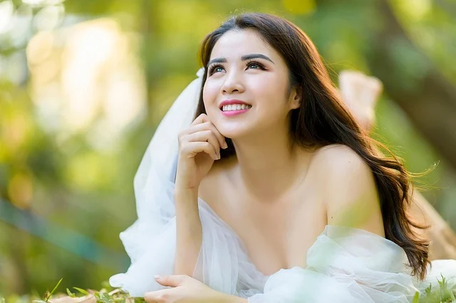 Gowns for women: A smiling woman wearing a white off-the-shoulder gown outdoors
