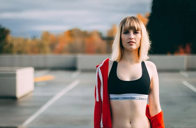 A woman wearing a sports bra and red jacket outdoors