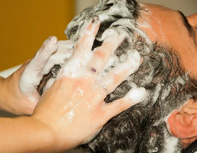 Hands washing a man's scalp with foamy shampoo