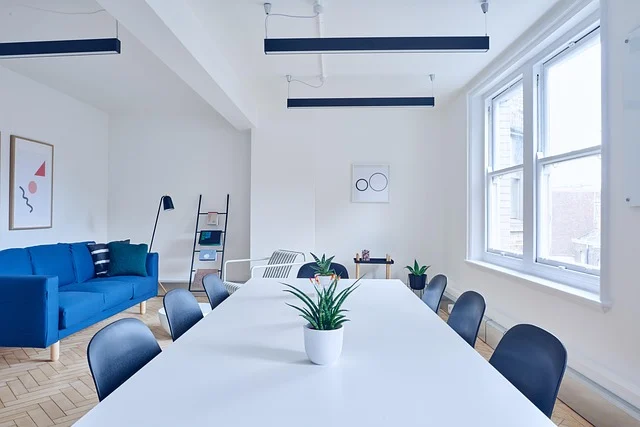 A modern office conference room with a white table and blue sofa