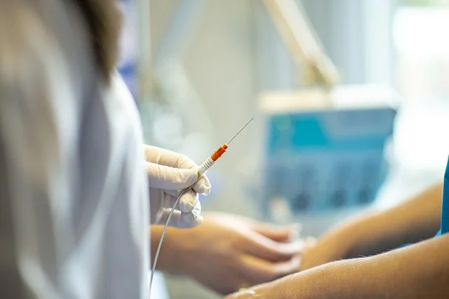 A gloved practitioner holding a fine needle for a medical procedure