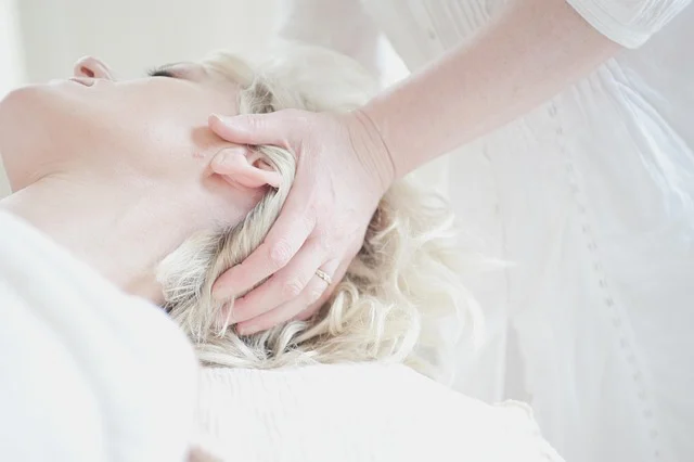 A woman receiving a scalp massage from a practitioner