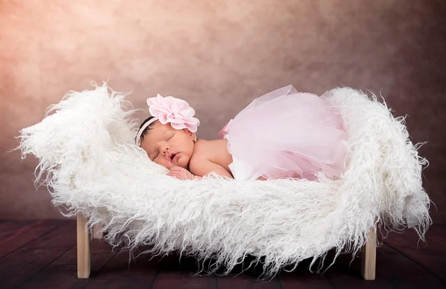 Sleeping newborn baby wearing a pink tutu on a fluffy blanket