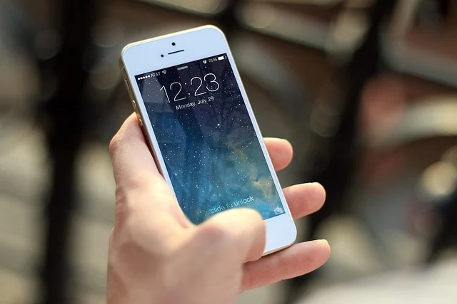 A hand holding a white smartphone showing the lock screen