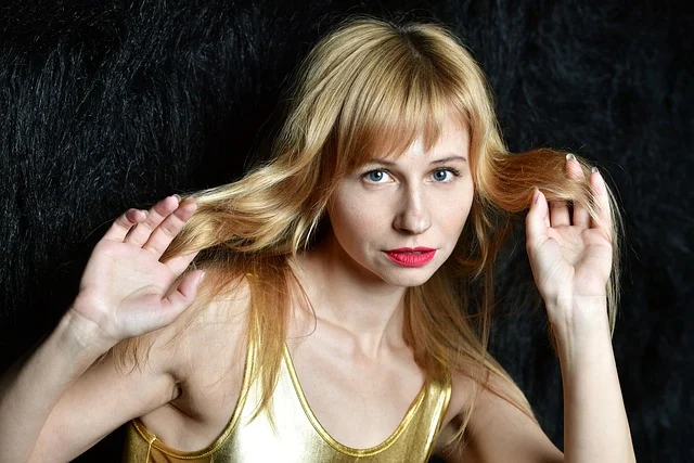 A blonde woman holding and touching her hair
