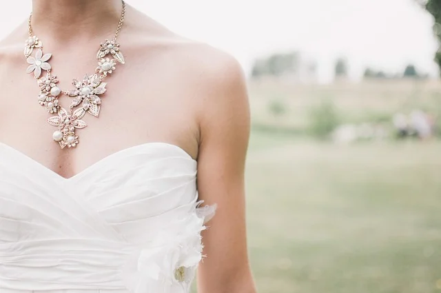 A bride wearing a strapless wedding dress and ornate floral necklace