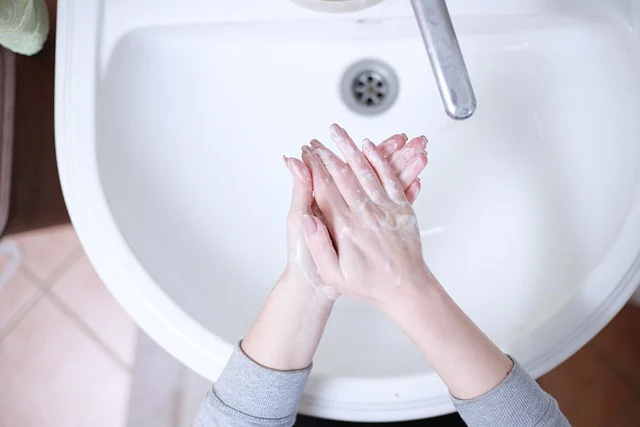 Soapy hands being washed over a white bathroom sink