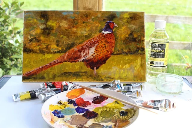 An oil painting of a pheasant surrounded by paints and palette