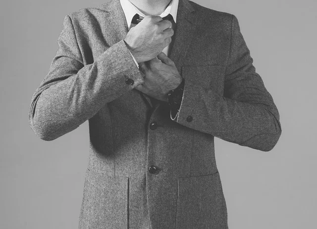 A man adjusting his tie while wearing a suit jacket