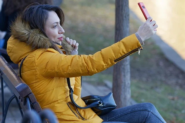 A woman taking a selfie outdoors wearing a yellow winter jacket