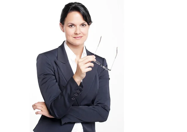 A professional woman in a dark blazer holding eyeglasses