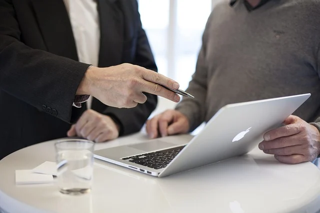 Two people discussing information on a laptop during a meeting