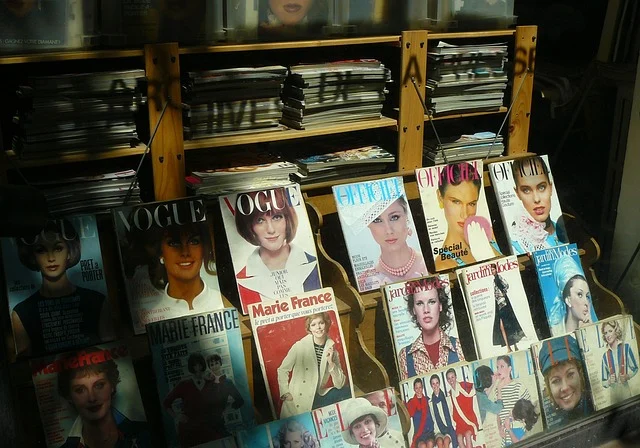 A display shelf filled with vintage fashion magazines like Vogue and Elle