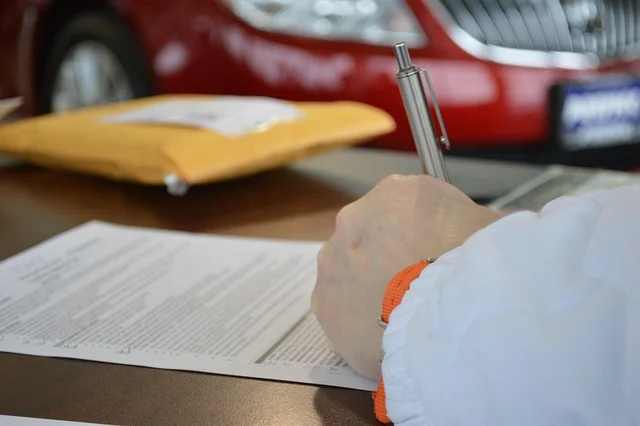 A person filling out a paper document with a pen